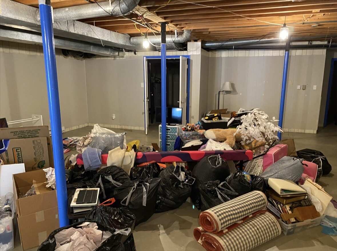 Before basement cleanout in Charlotte NC — full basement packed with furniture, boxes, and debris